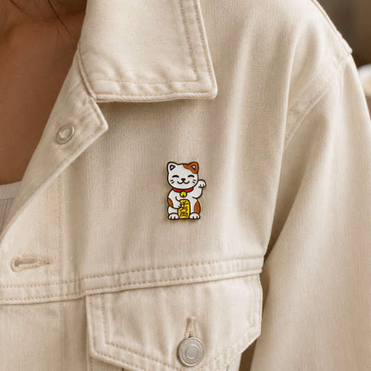 Gold and red Lucky Cat enamel pin with a smiling face and raised paw, ideal for accessories and collectibles.