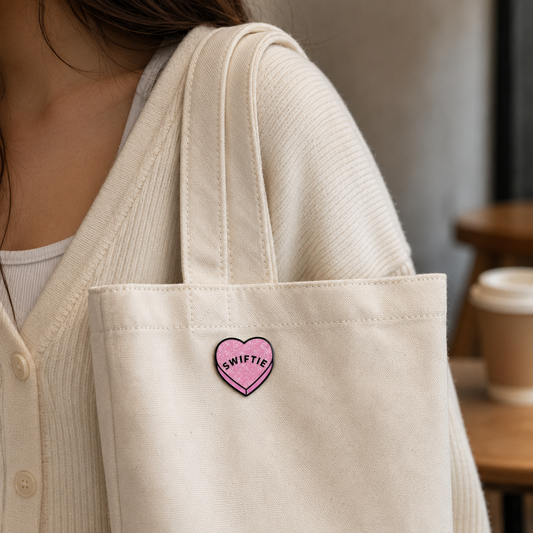 Pink "Swiftie" enamel pin by Pinlord.com, featuring a shiny heart design, perfect for fans and accessory collections.