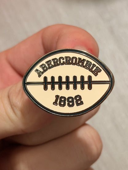 Abercrombie & Fitch Super Bowl after-party custom enamel pins displayed on a project board.