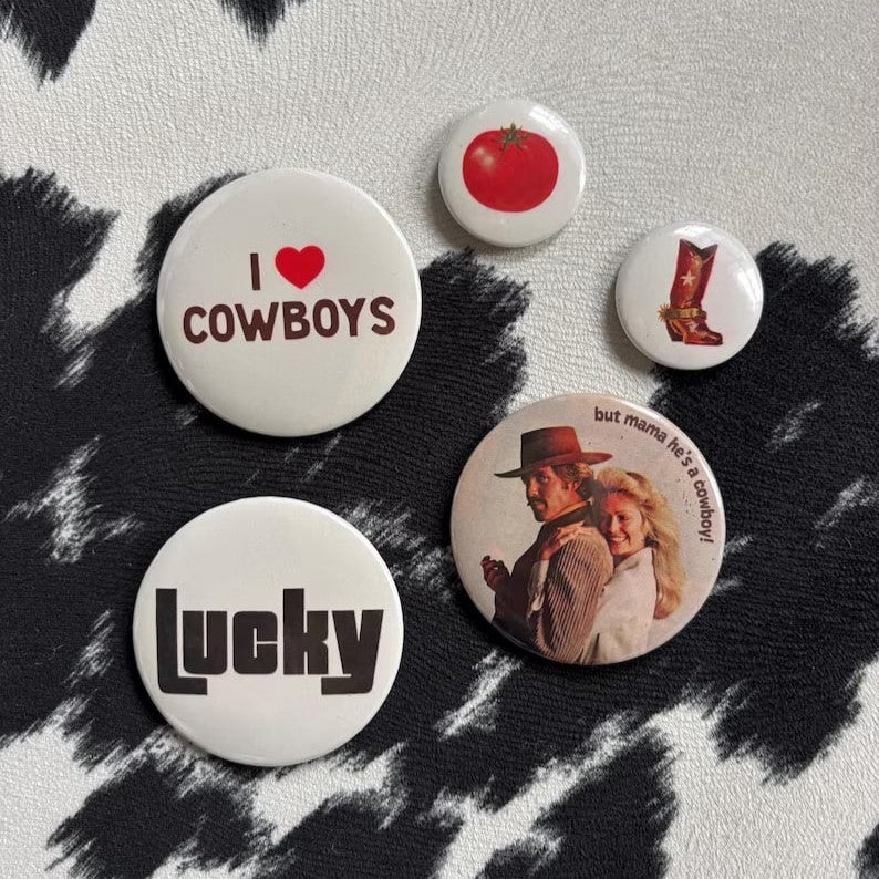 Custom button pins featuring unique badge designs from Pinlord.com, shown on a neutral background.