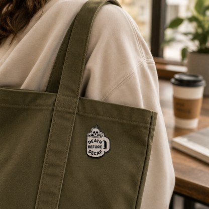 Skull enamel pin featuring "Death Before Decaf" design, black and white detailed metal pin, perfect for accessories or jackets.