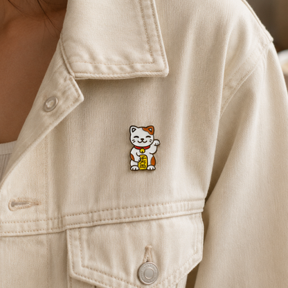 Gold and red Lucky Cat enamel pin with a smiling face and raised paw, ideal for accessories and collectibles.