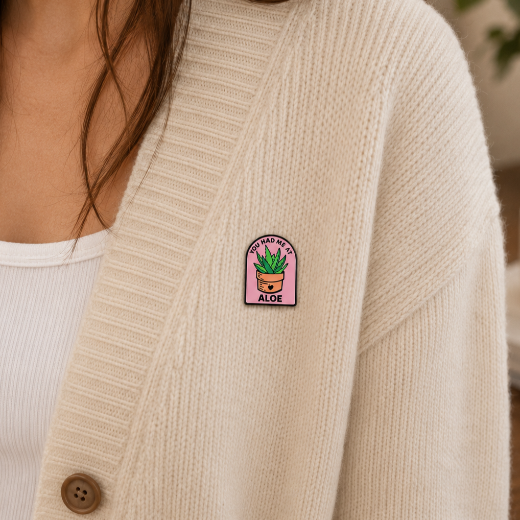 Aloe plant enamel pin featuring a cute green aloe leaf design, perfect for accessorizing clothing or backpacks.