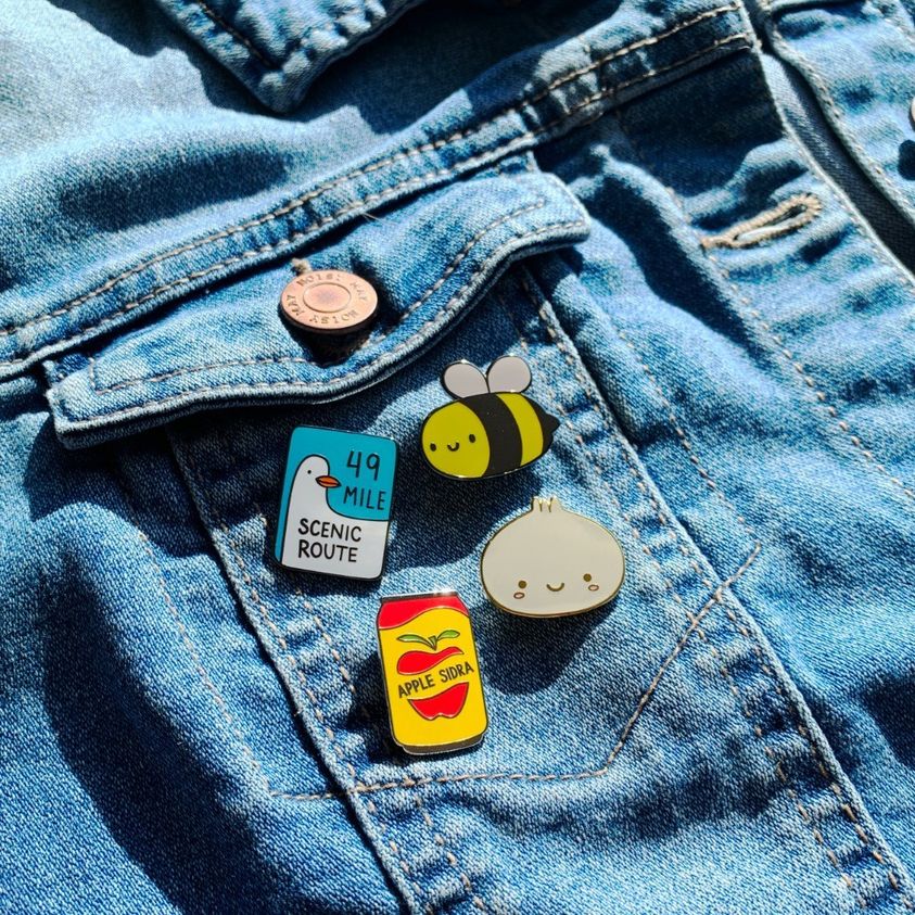 Custom enamel pins by Pinlord.com featuring colorful, detailed designs on a metal backing, perfect for accessories or collectibles.