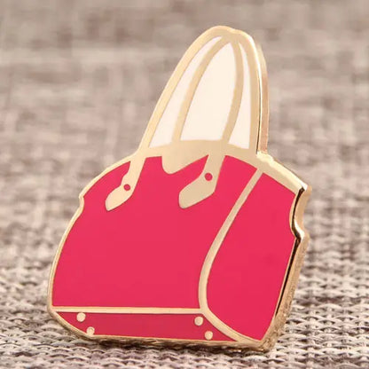 Close-up of colorful enamel handbag pins from Pinlord.com, showcasing detailed designs on a light background.
