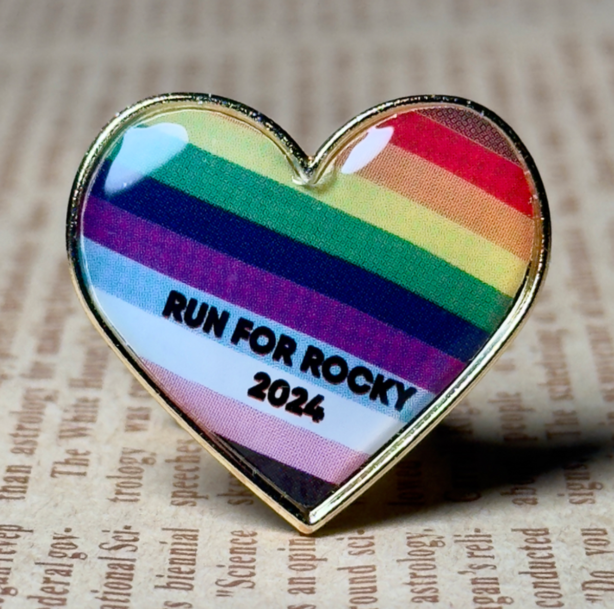 Close-up of a Pinlord.com lapel pin with "Now Review" design on a textured fabric background.