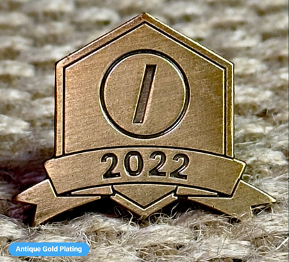 Close-up of a Pinlord.com lapel pin featuring the Now Review design, showcasing detailed craftsmanship on a metallic finish.