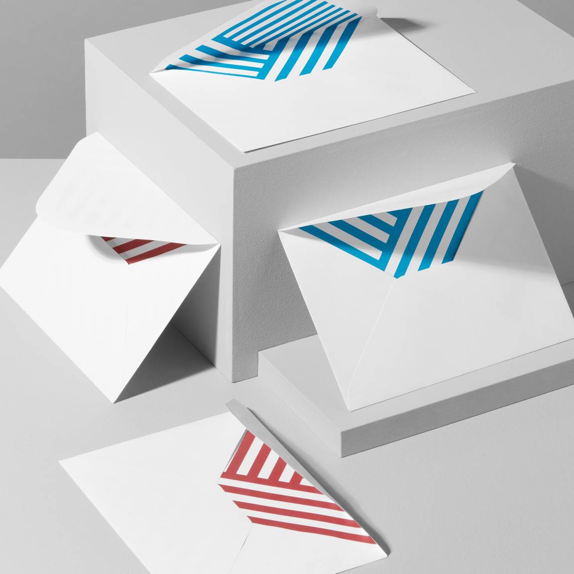 Close-up of white manufacturer envelopes with Pinlord.com branding, made by MOO Review, showing smooth texture and sealed flaps.