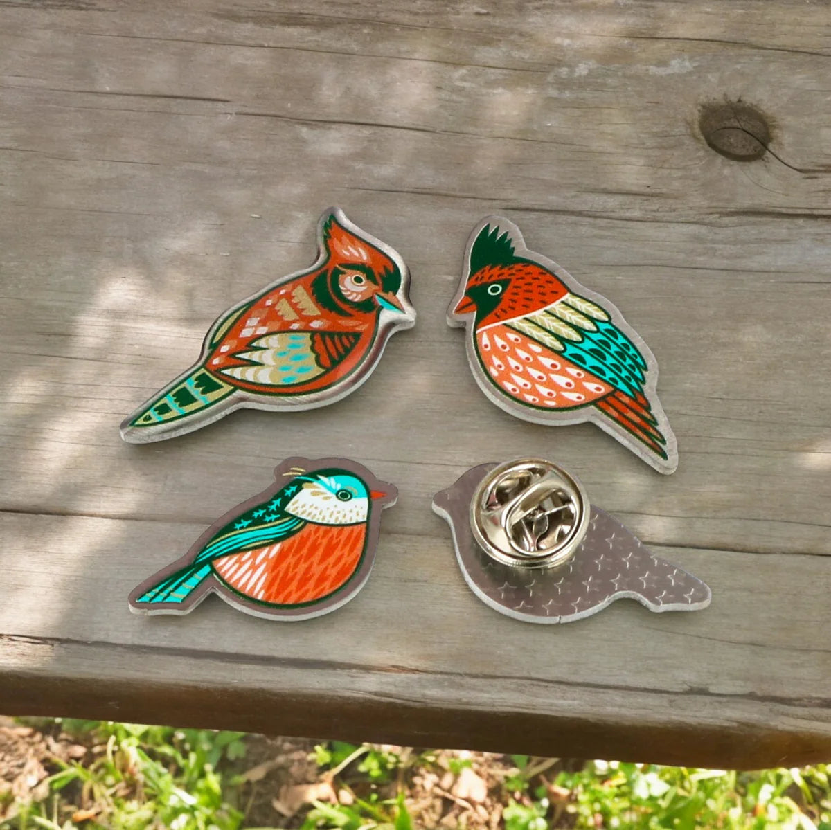 Custom metal enamel pin badges by Pinlord.com, showcasing detailed designs on a shiny metal surface.