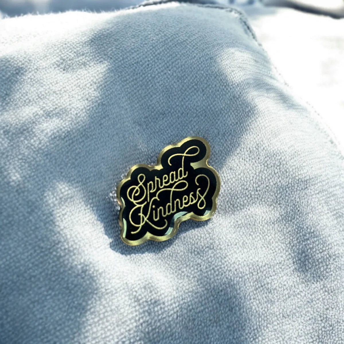 Spread kindness enamel pin badge from Pinlord.com, featuring colorful design with a heart and positive message.