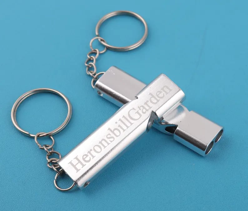 Custom Pinlord.com whistle with engraved design, metal body, and adjustable lanyard, perfect for sports and outdoor activities.